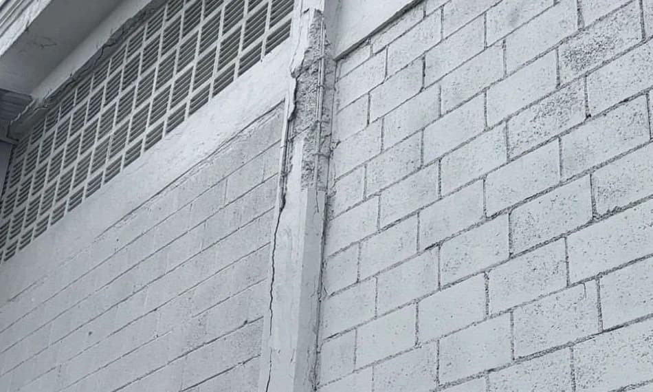Pilar de concreto com fissuração, perda de material e armadura aparente em complexo operacional