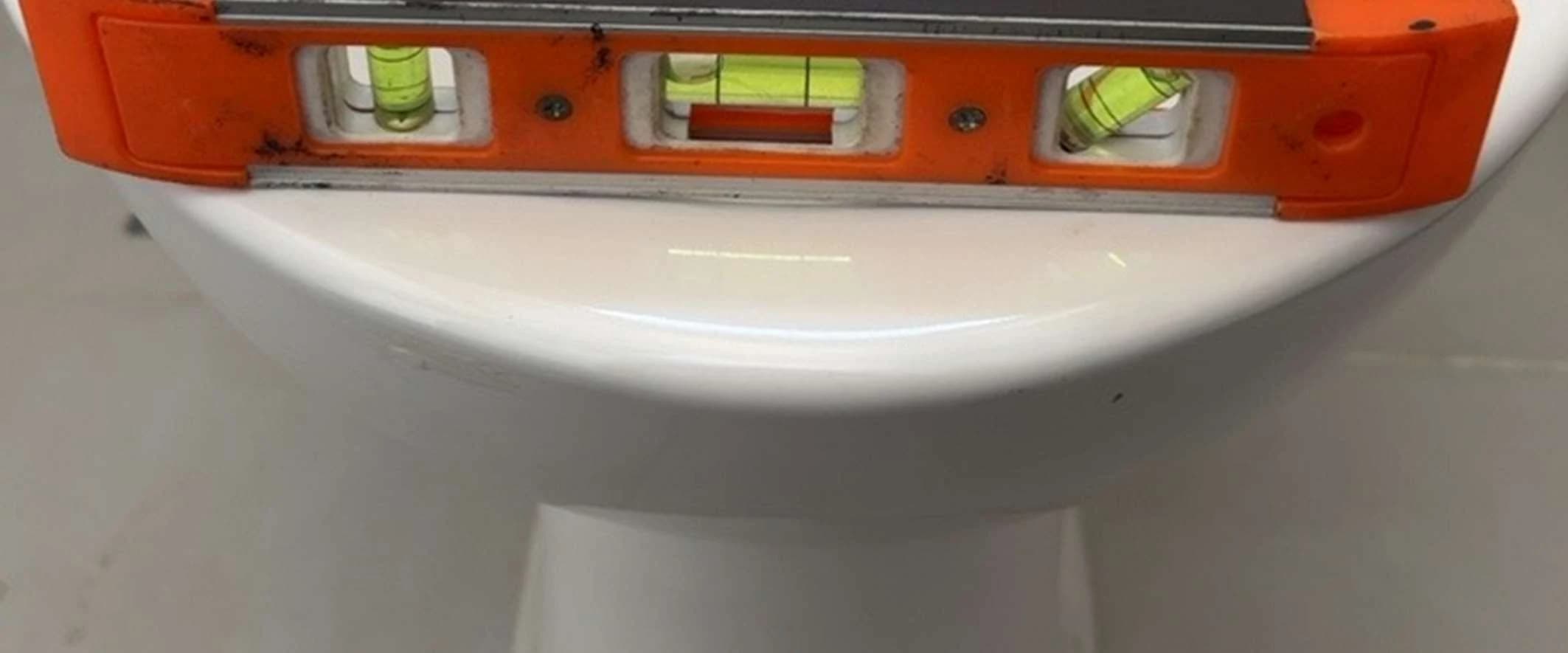 Nível de bolha apoiado sobre bacia sanitária durante conferência de instalação